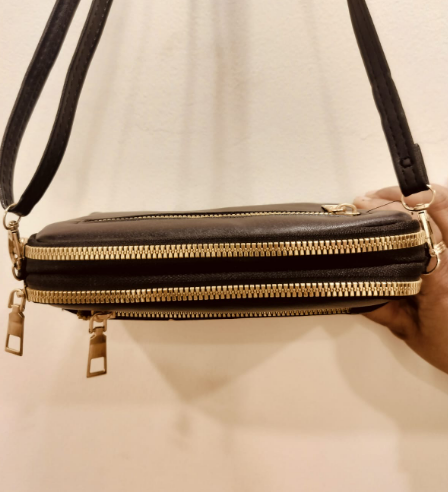 Black crossbody purse with chains featuring multiple gold zippers and adjustable strap