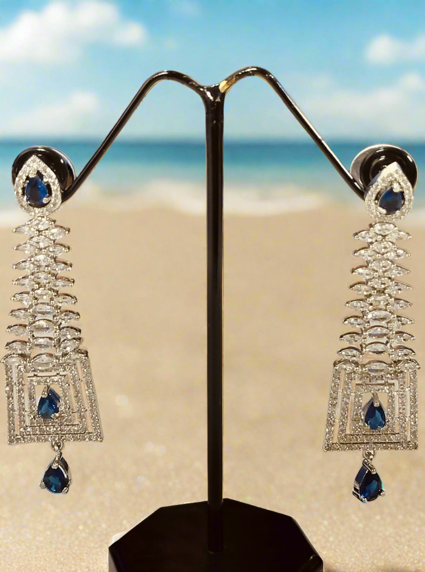Blue stone dangle Ad earrings for Party with silver setting displayed on black stand