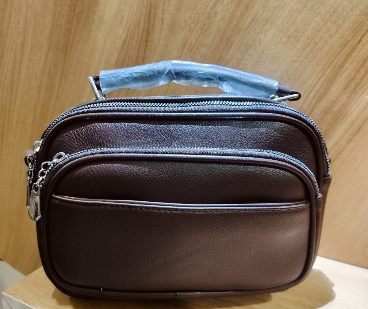 Brown leather bag with multiple zippered compartments and wrapped handle for easy carrying