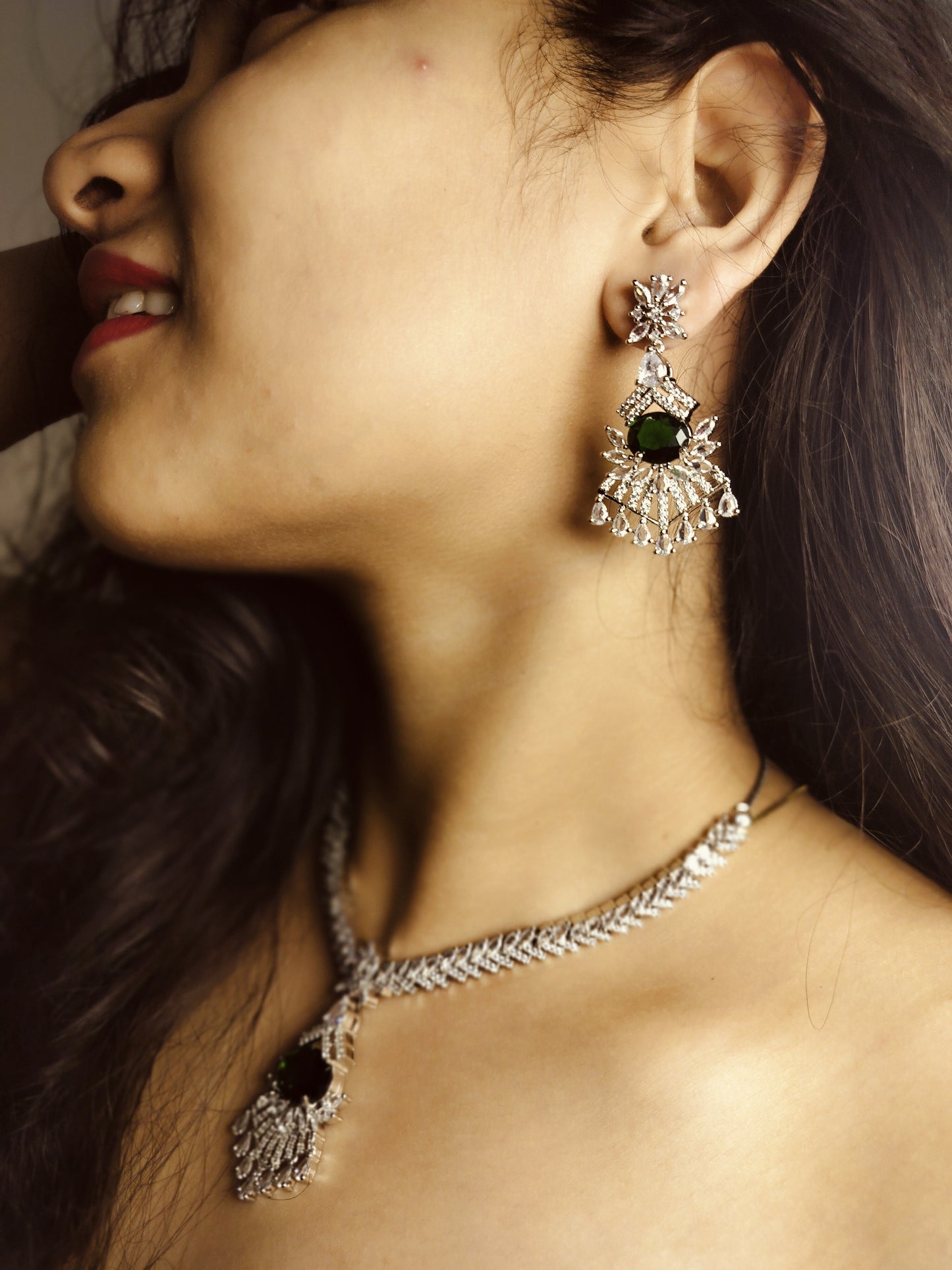 Green AD stone necklace and earring set featuring intricate silver design worn by woman