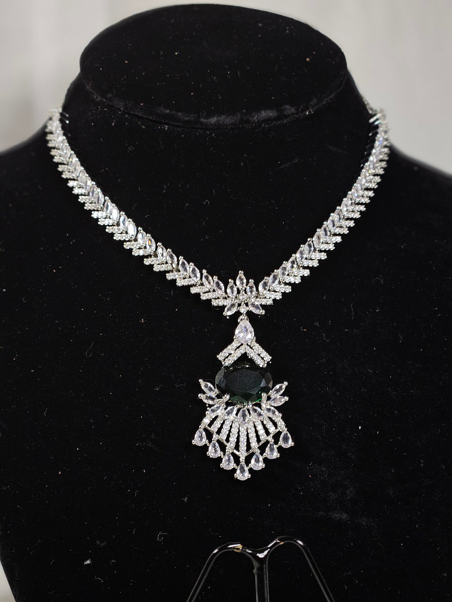 Green AD stone necklace and earring set with intricate silver detailing displayed on black velvet stand
