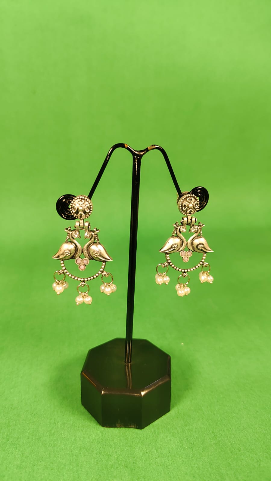 Green indo-western earrings alloy silver with bird design and dangling charms on black stand
