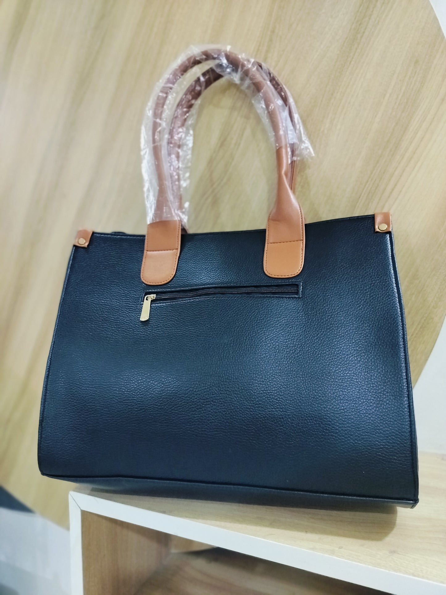 Handmade leather laptop tote in black with brown handles and front zipper pocket by Wincham Fashion House