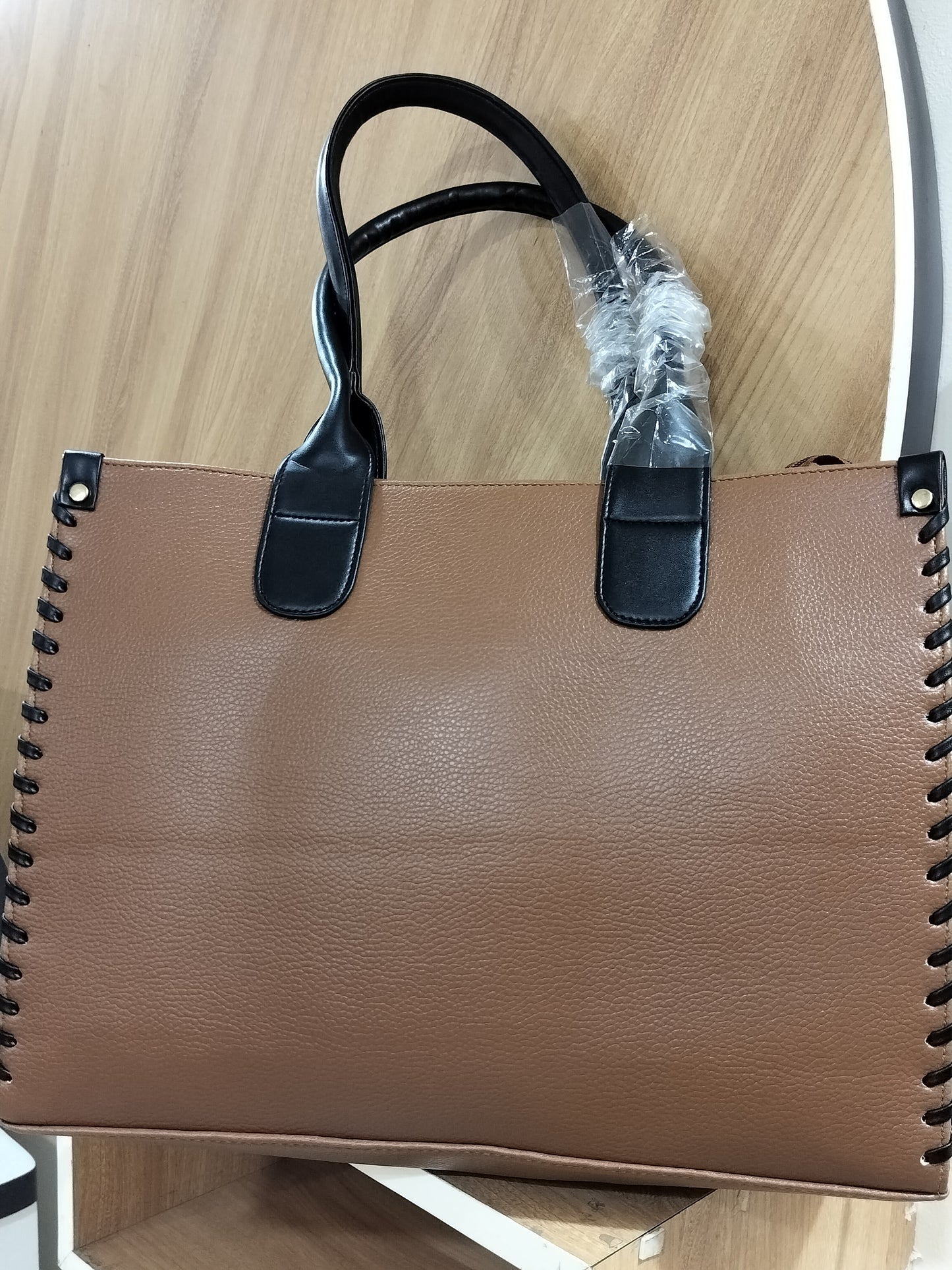 Wincham Fashion House handmade leather laptop tote in brown with black handles on wooden surface