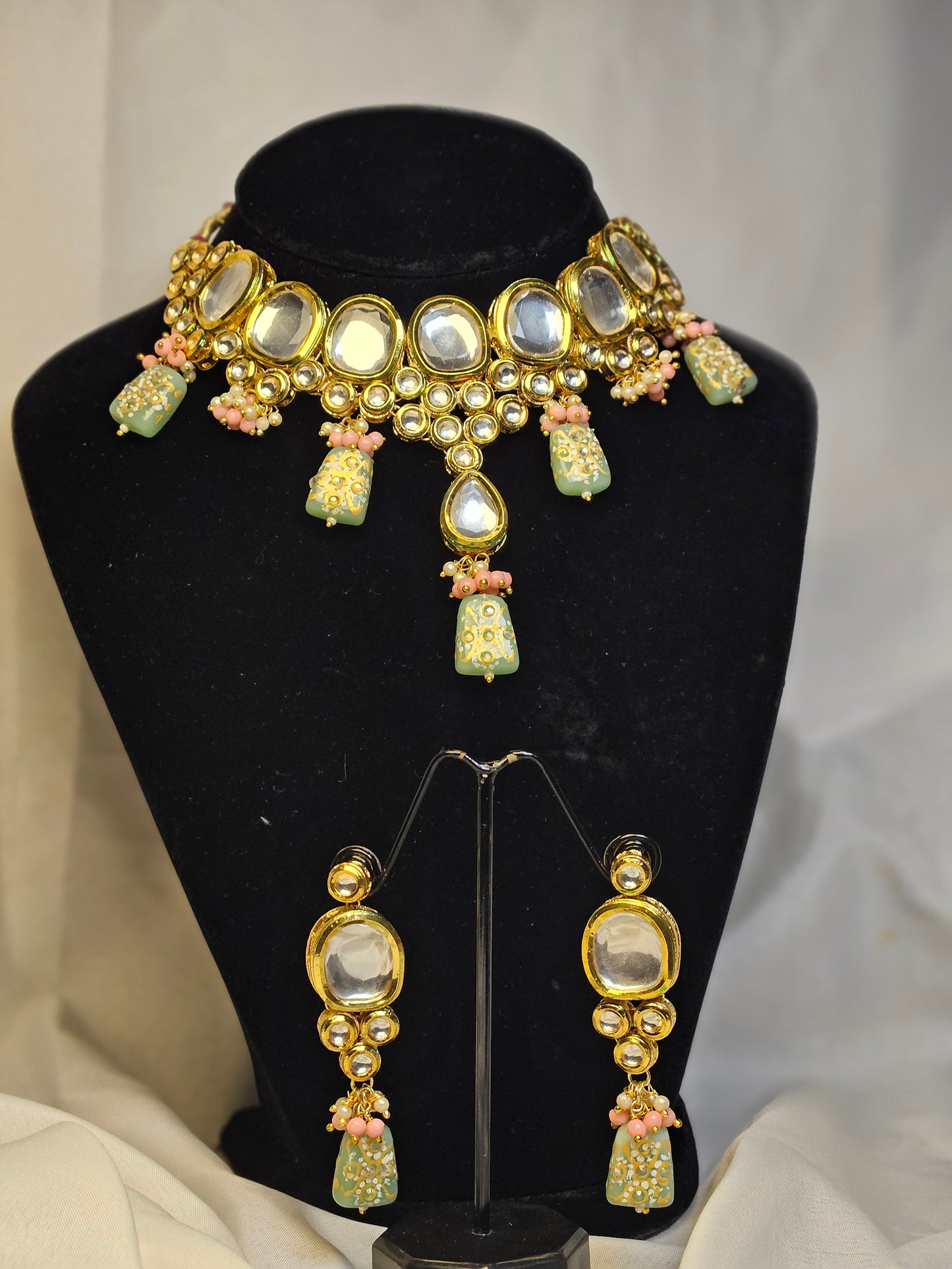 Pink and green Indian jewelry set featuring a mirror-studded gold choker necklace and matching earrings