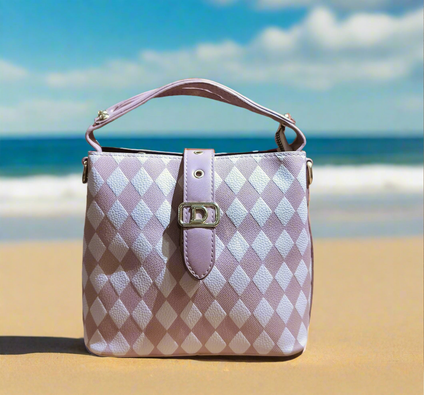 Pink leather purse for women with diamond pattern and buckle detail standing on sandy beach