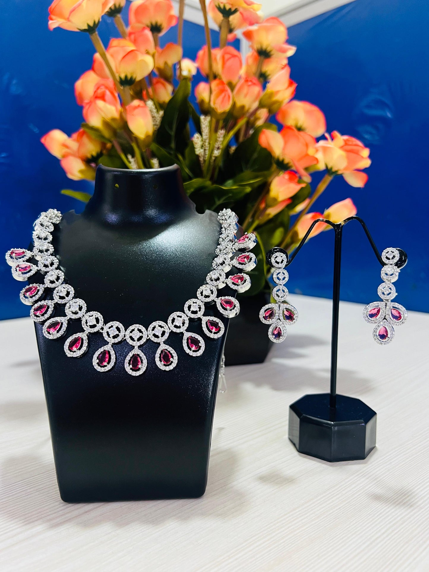 Ruby leaf crystal necklace set with sparkling red and clear stones displayed on black stands
