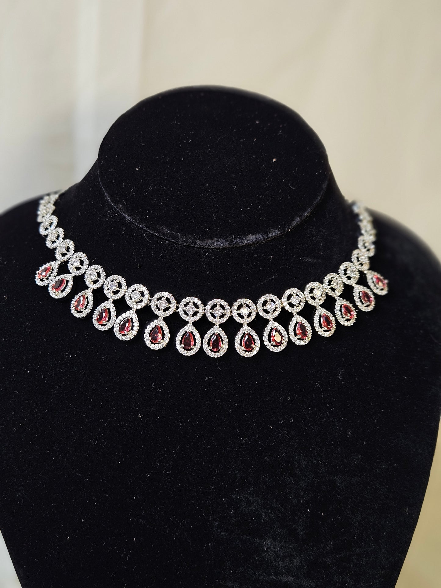 Elegant ruby leaf crystal necklace set with red teardrop stones and silver detailing on black velvet stand