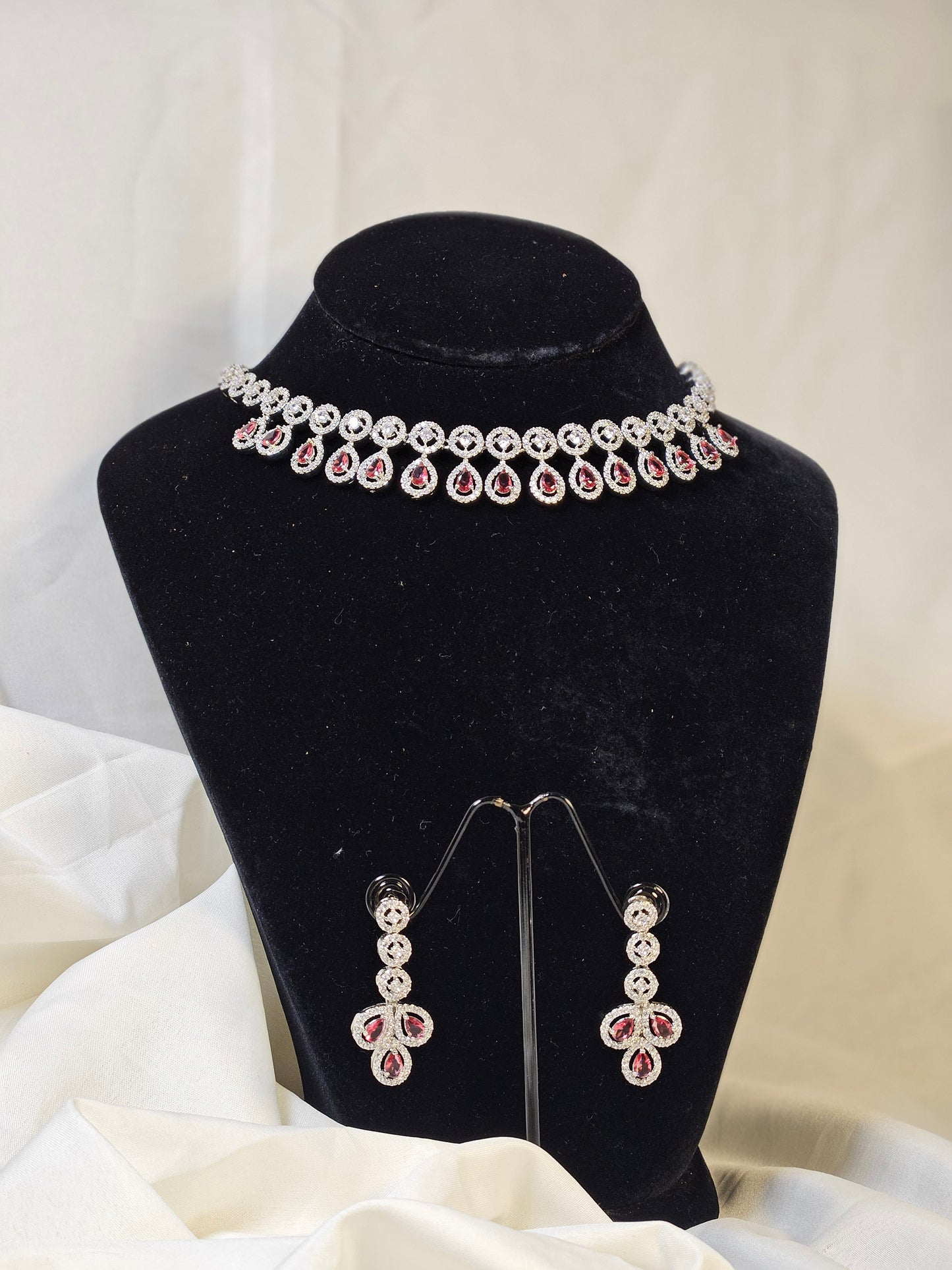 Ruby leaf crystal necklace set with matching earrings displayed on black stand