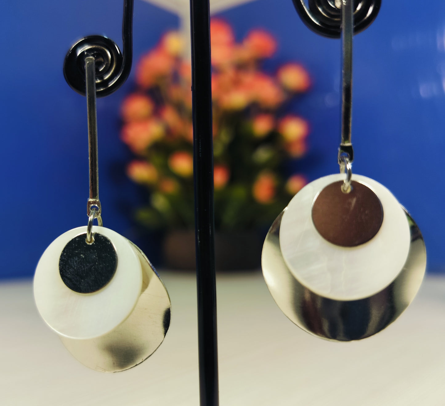 Wincham Fashion House silver and gold seashell earrings with layered circular design hanging on display stand
