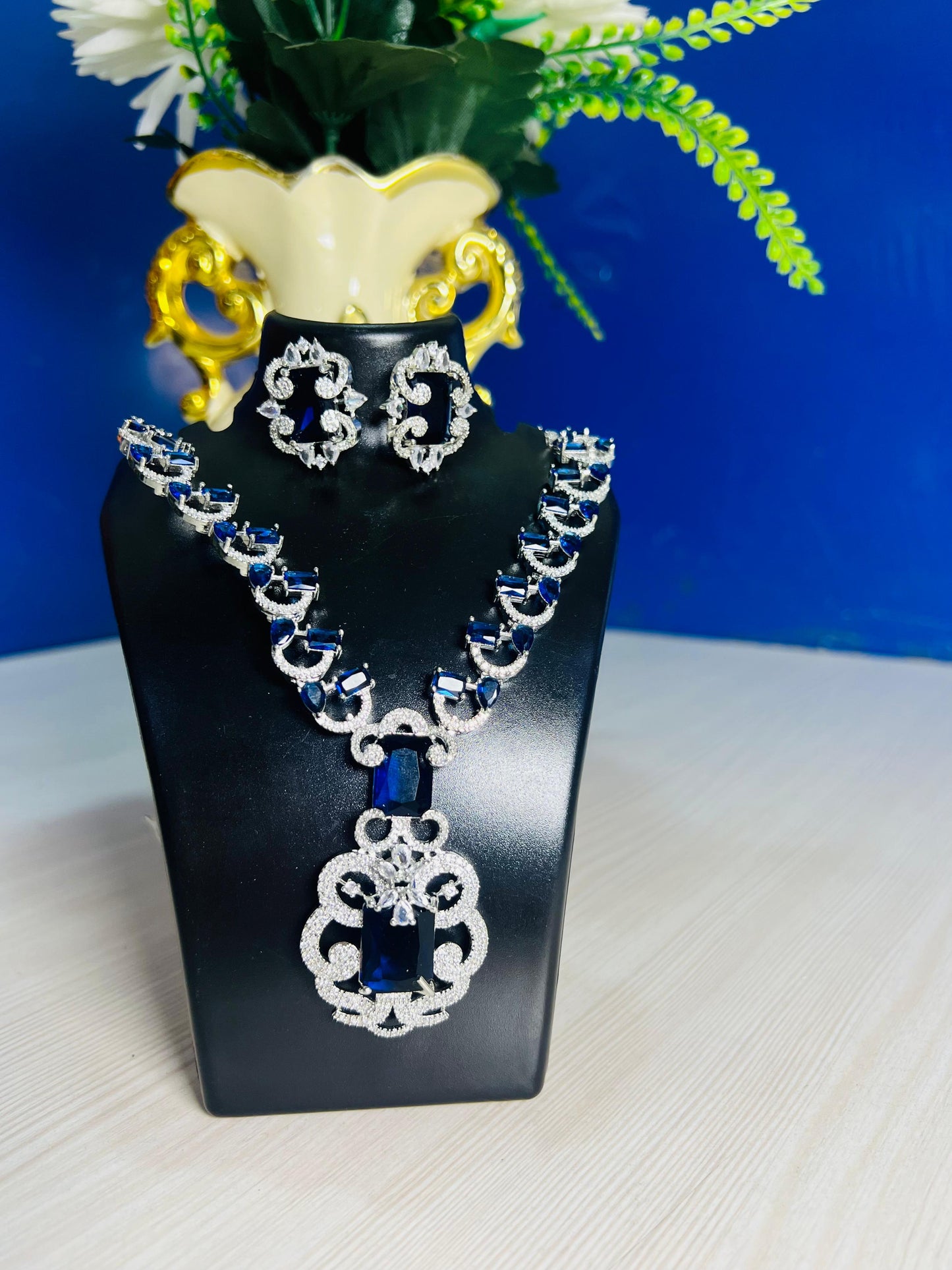 Elite royal blue design necklace set for weddings with matching earrings on black display