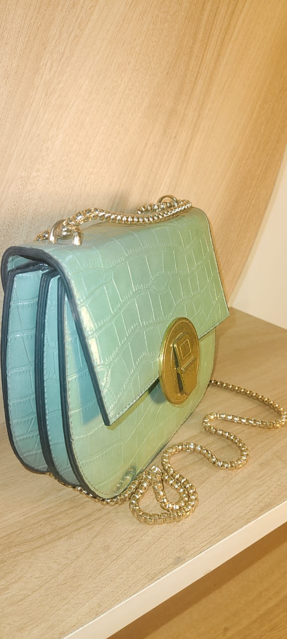 Light green leather bag with gold chain and clasp on wooden surface at My Store