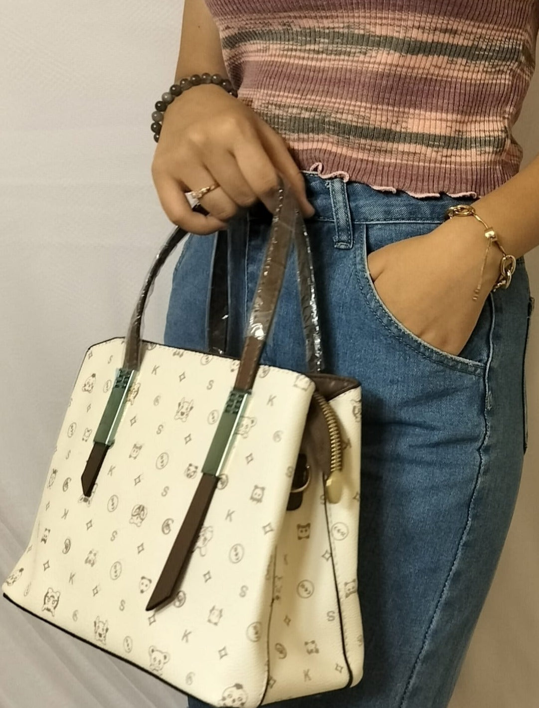 Woman holding a white designer bag with brown and green accents green shoulder bag for women