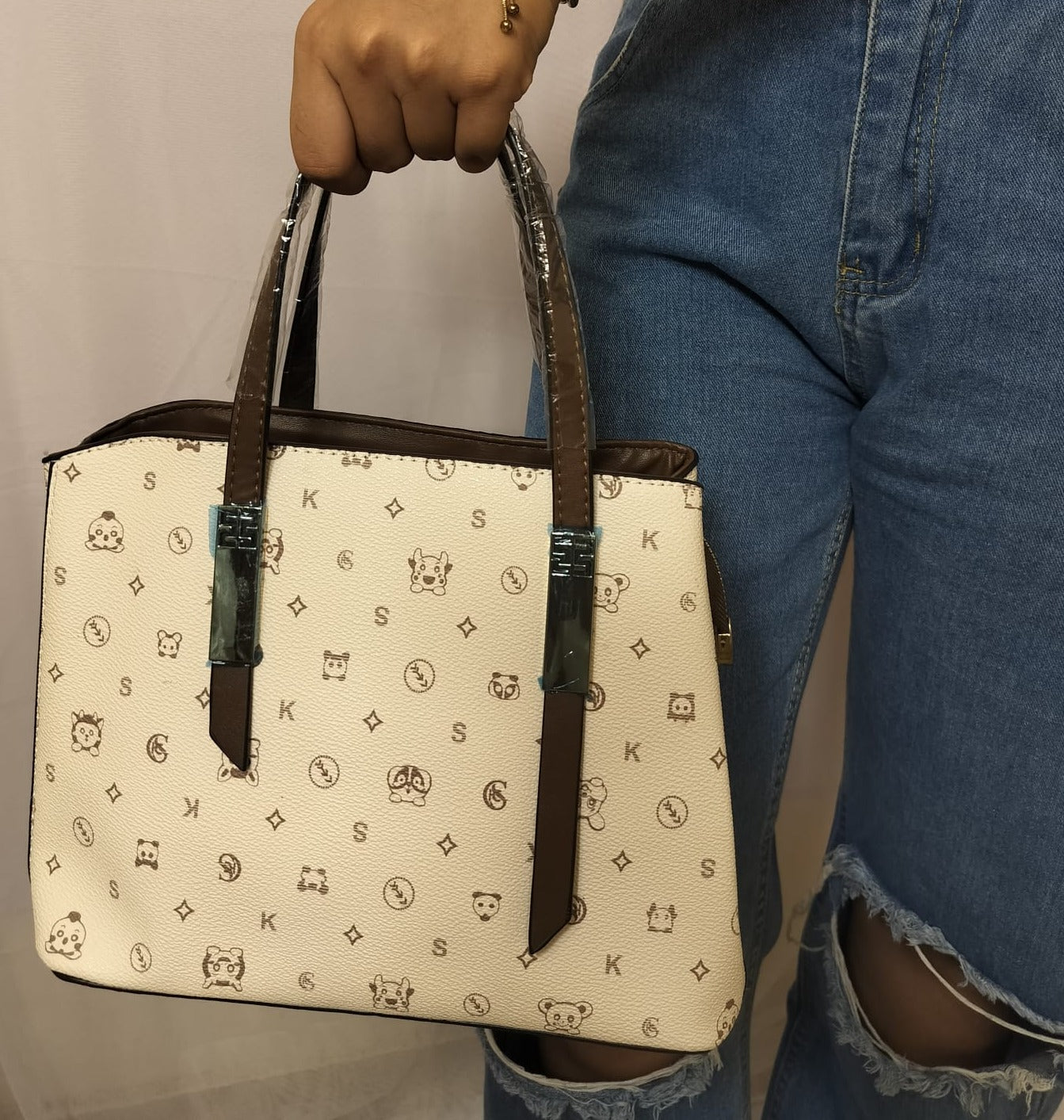 Green shoulder bag for women held by hand with brown handles and patterned beige body
