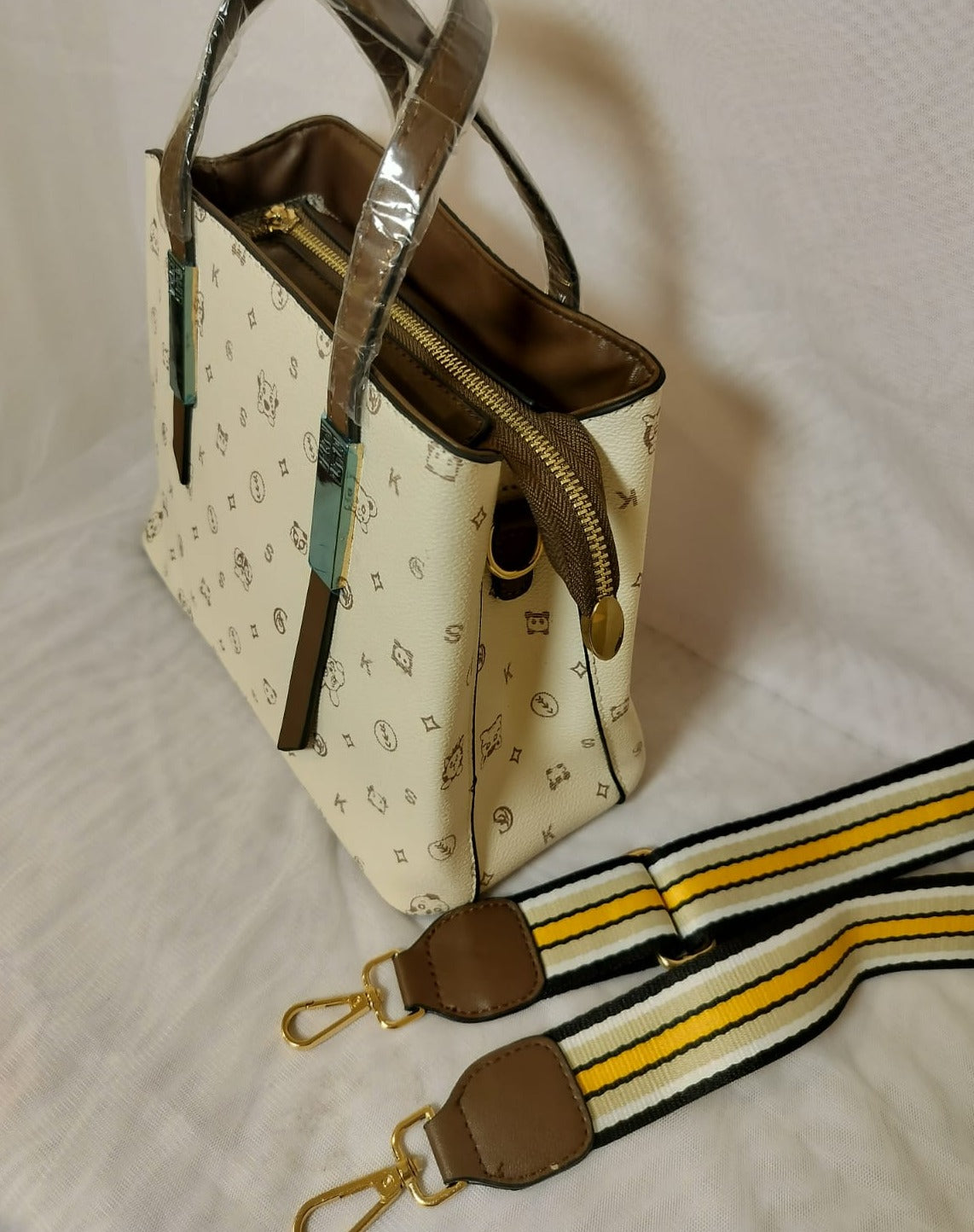 Cream colored bag with brown accents and detachable striped strap, green shoulder bag for women
