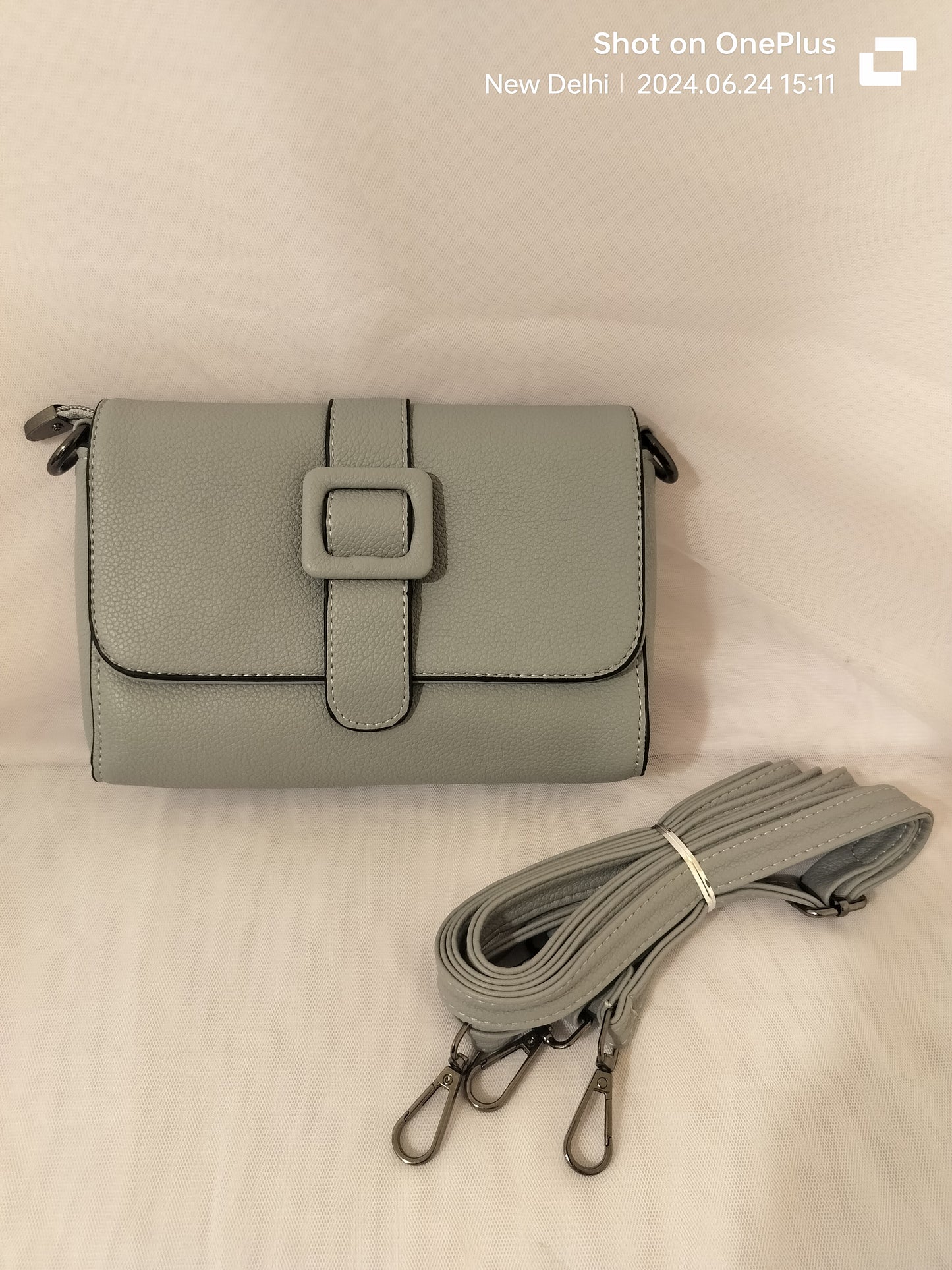 Gray women's leather crossbody bag with adjustable strap and buckle detail