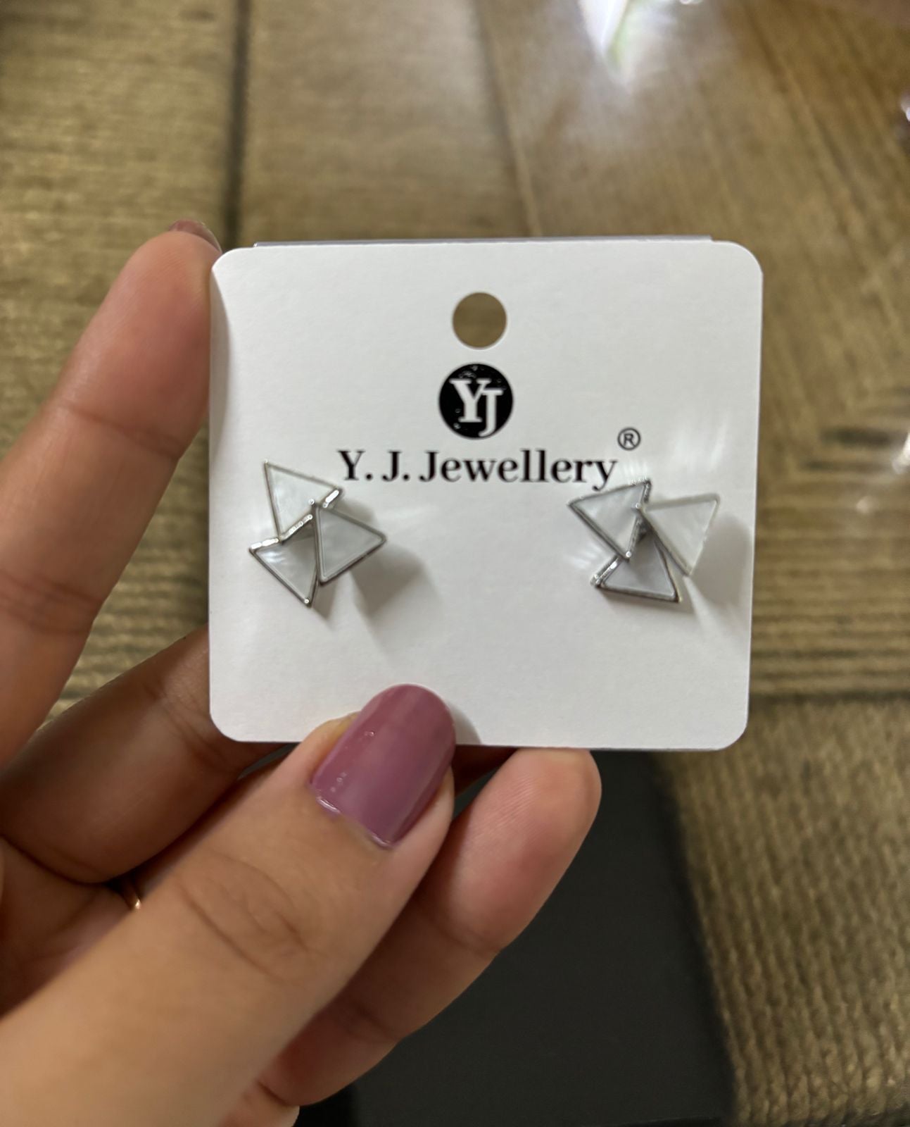 Korean triangle silver earrings displayed on Y.J. Jewellery card held by hand