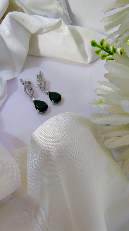 Wincham Fashion House American diamond green drop earrings displayed on white fabric with floral accents