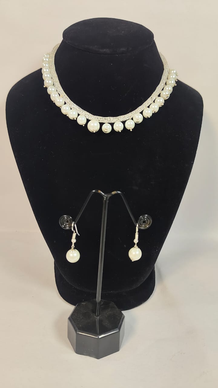 Elegant antique cubic zirconia pearl necklace with matching pearl drop earrings displayed on a jewelry stand