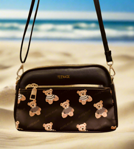 Black crossbody purse with chains featuring teddy bear print and front zipper pocket