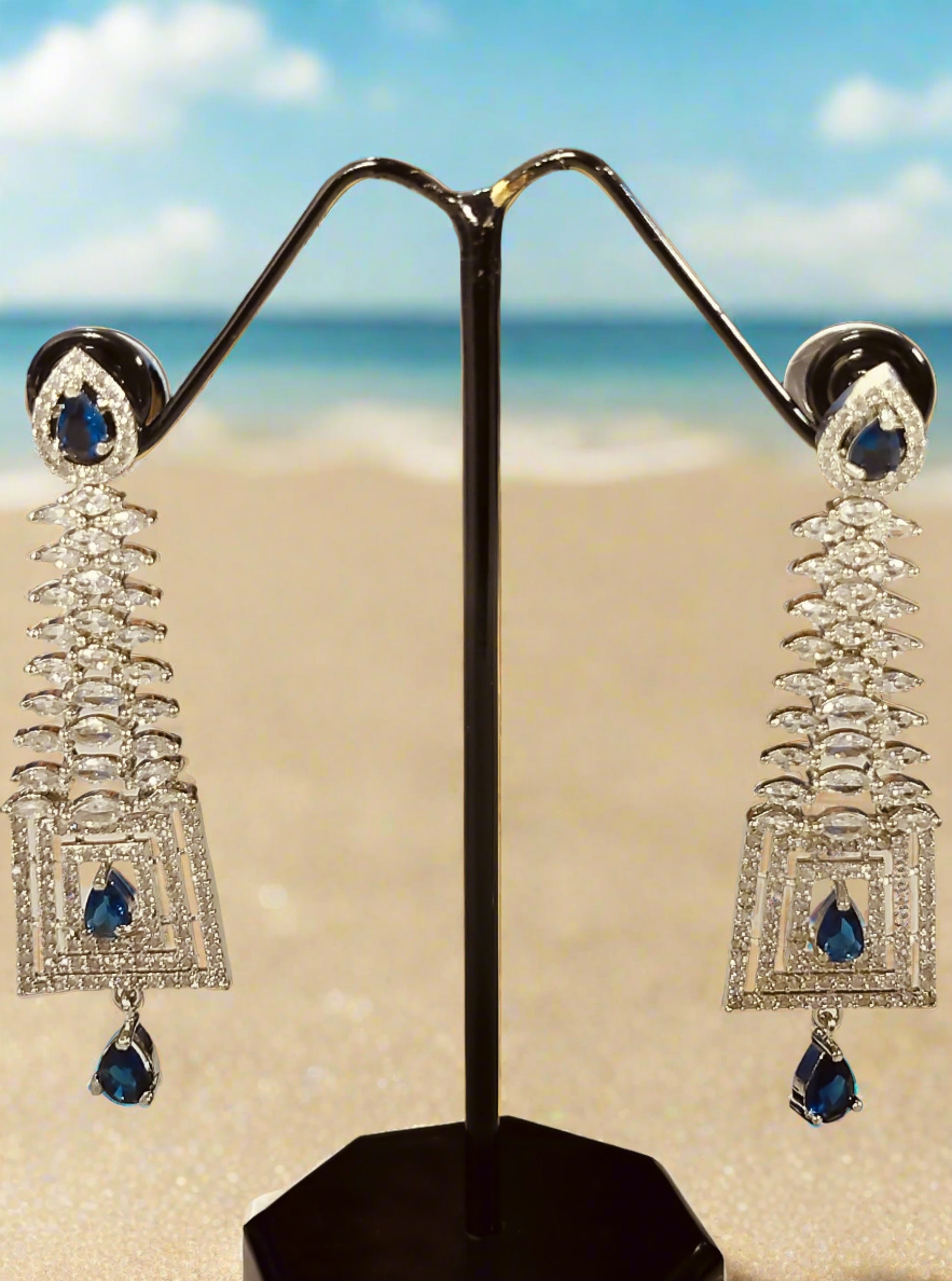Blue stone dangle Ad earrings for Party with silver setting displayed on black stand