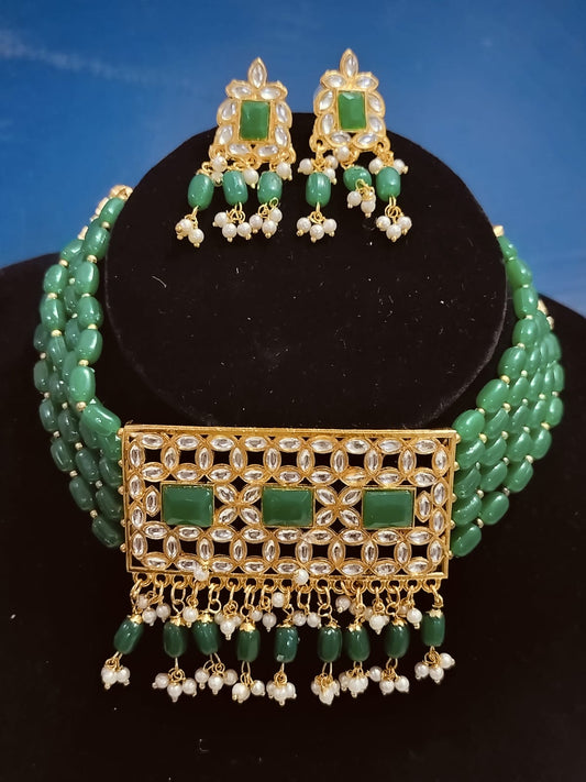 Elegant emerald green kundan choker set with matching earrings featuring intricate beadwork and pearl accents
