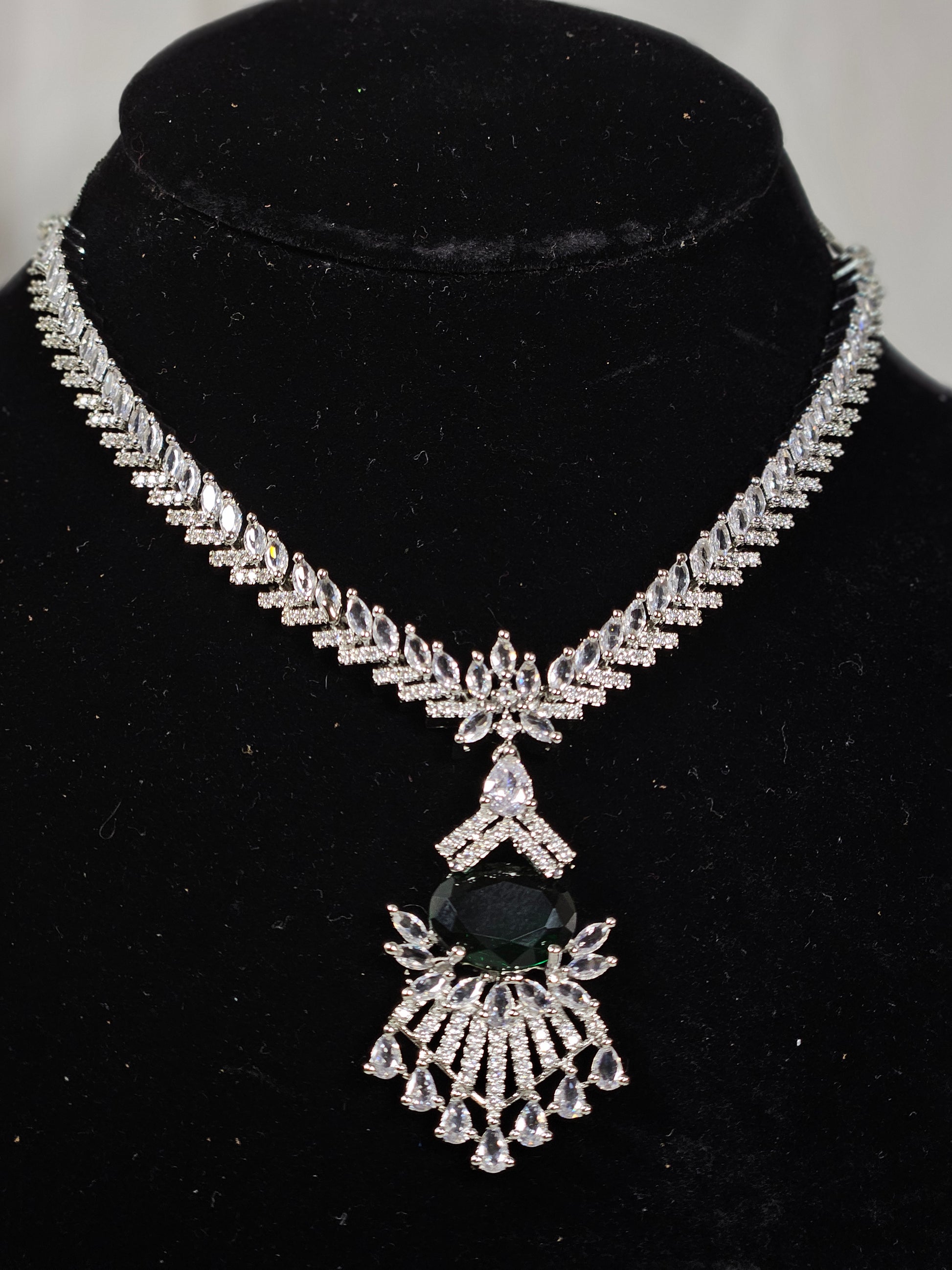 Wincham Fashion House Green AD stone necklace and earring set with intricate silver design on black display