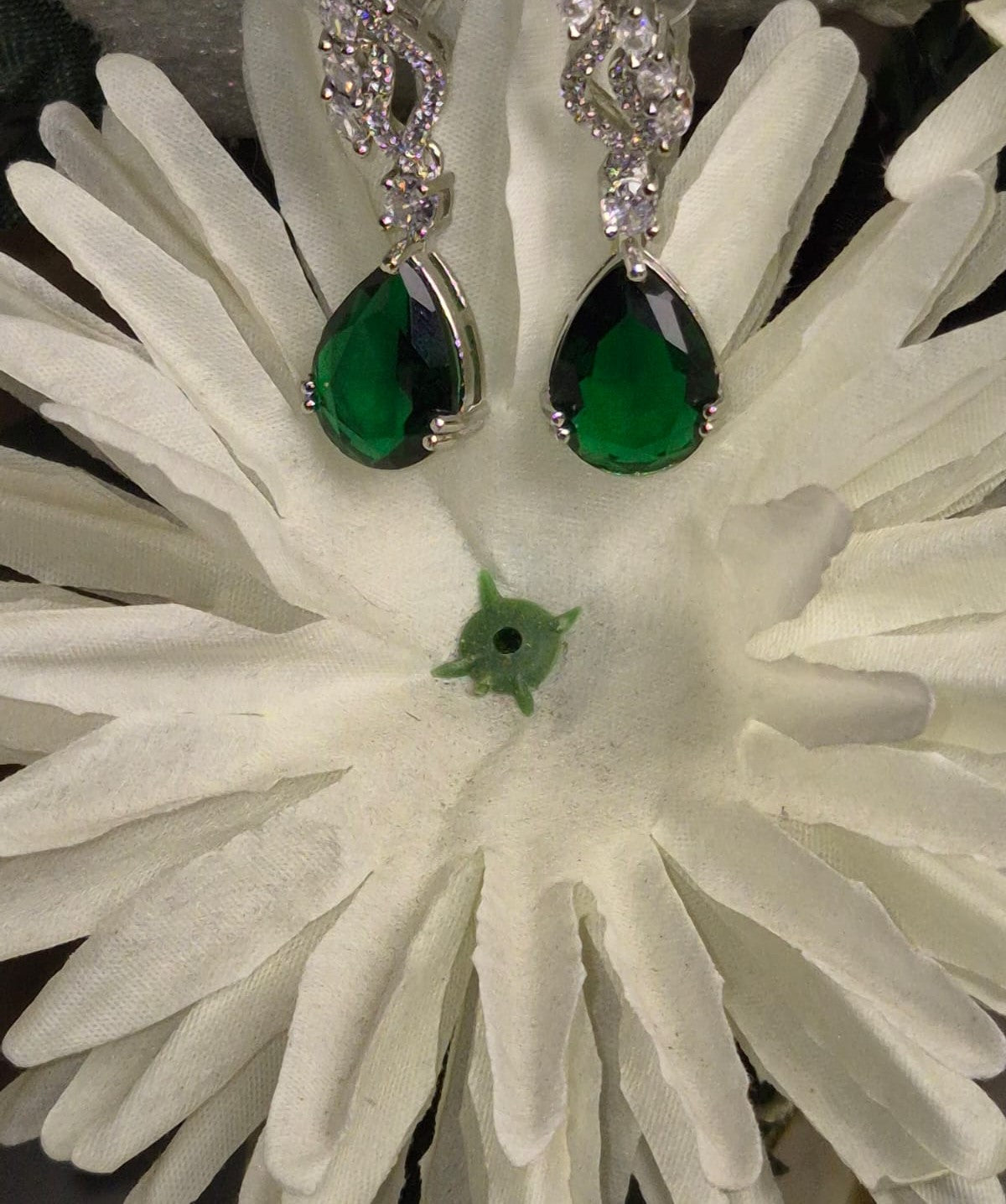 Wincham Fashion House Emerald drop earrings with silver settings displayed on textured white fabric