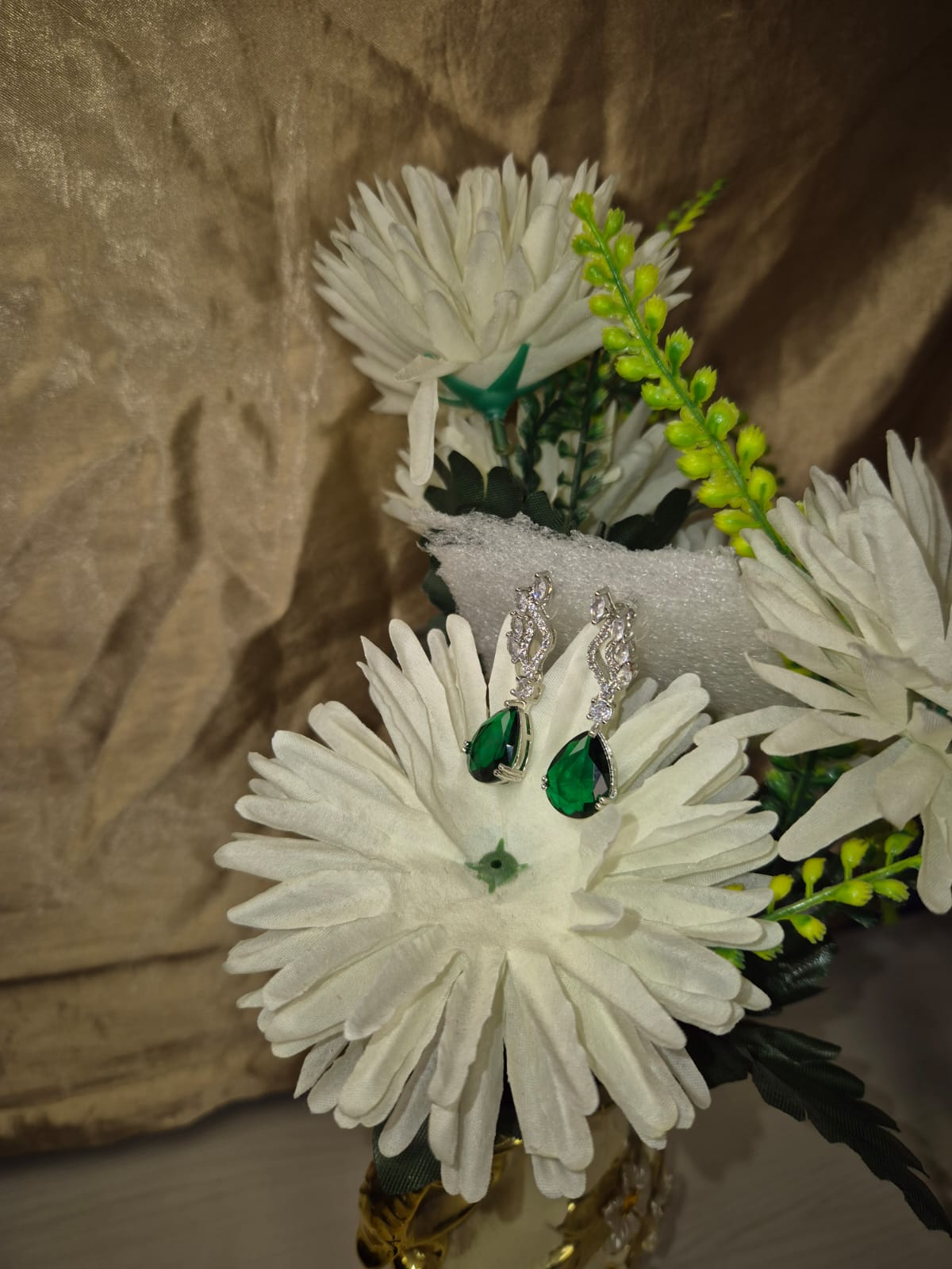 Wincham Fashion House emerald drop earrings with green teardrop stones and silver detailing on white flower