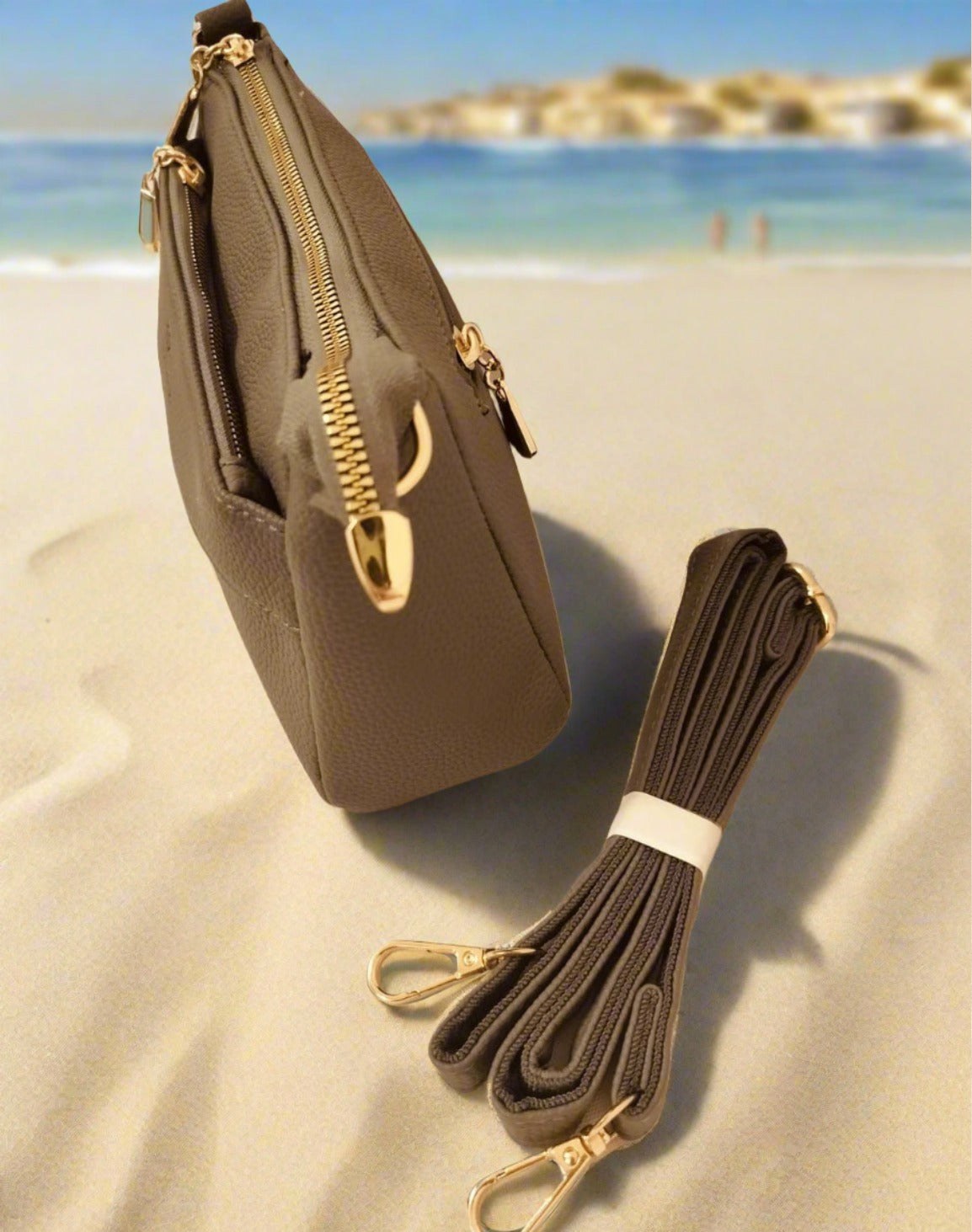 My Store women's crossbody bag grey with gold zippers and detachable strap on sandy beach background