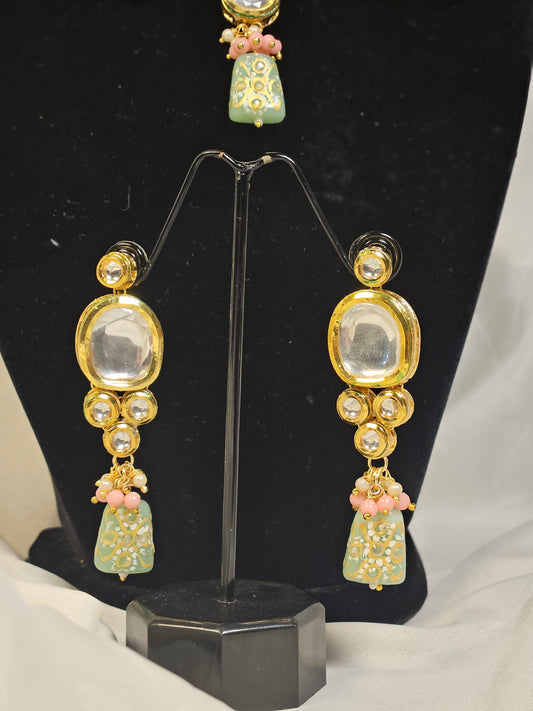 Pink and green Indian jewelry set featuring intricate earrings with gold and stone detailing