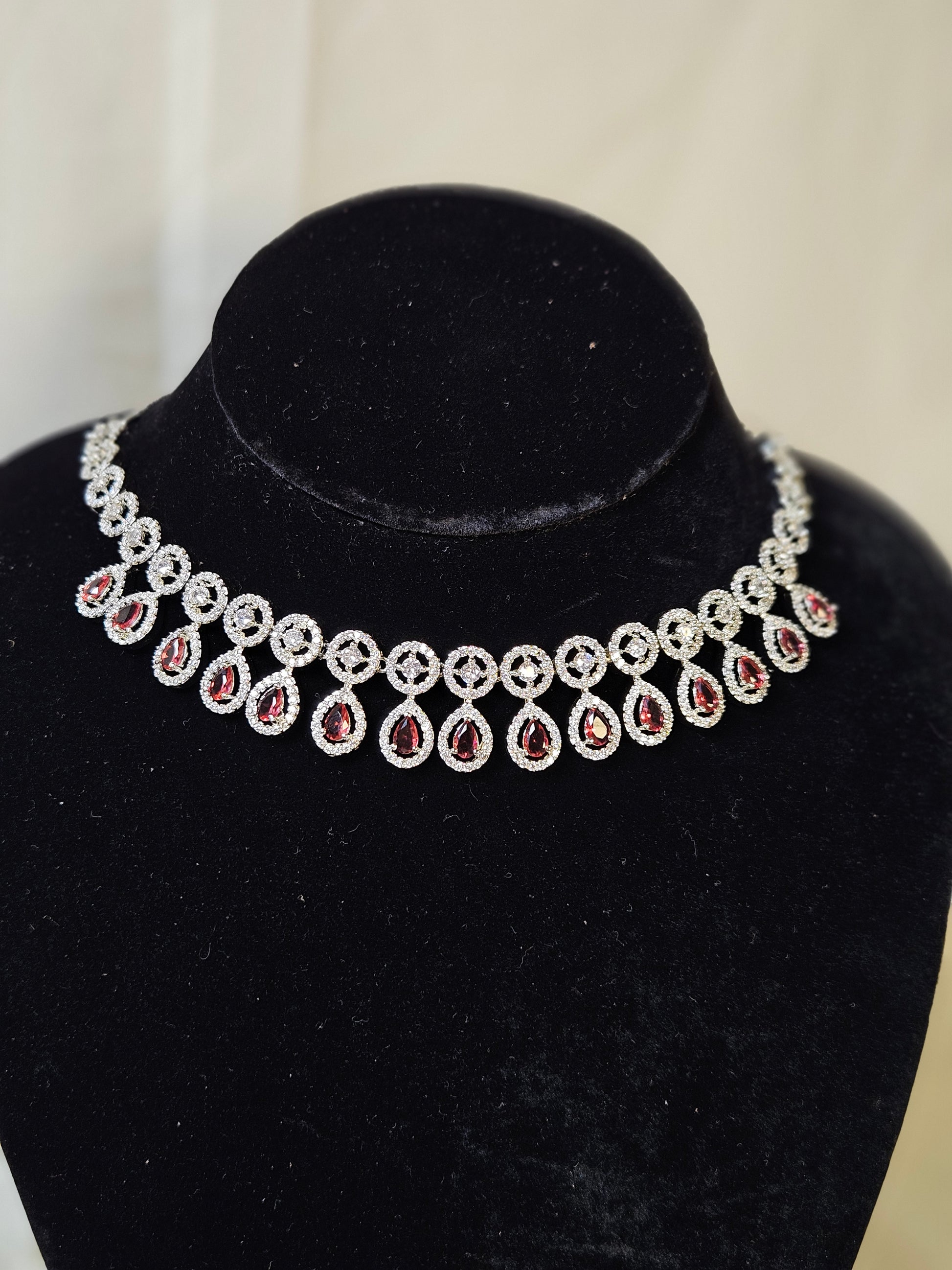 Elegant ruby leaf crystal necklace set with red teardrop stones and silver detailing on black velvet stand