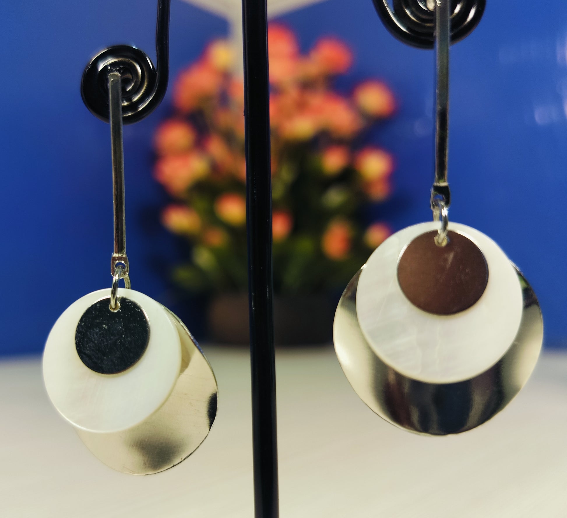 Wincham Fashion House silver and gold seashell earrings with layered circular design hanging on display stand