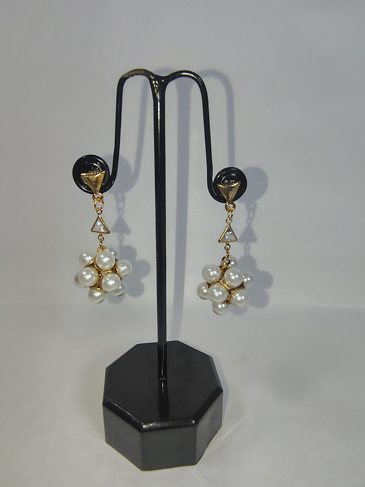 Elegant women with pearl earrings displayed on a black stand for a stylish accessory look