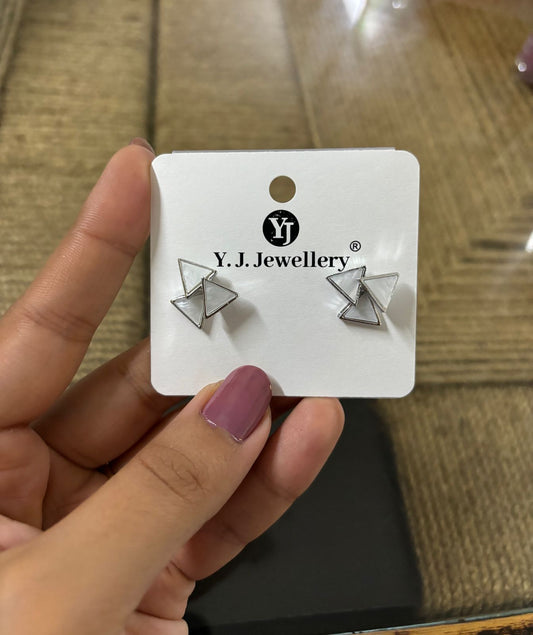 Korean triangle silver earrings displayed on a white card held by a hand with mauve nail polish